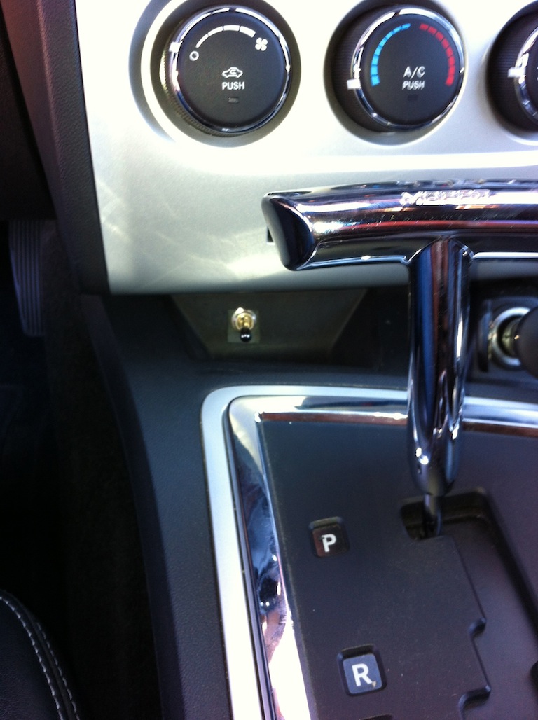 Car interior showing climate controls, a chrome shifter, and a toggle switch installed below the dashboard