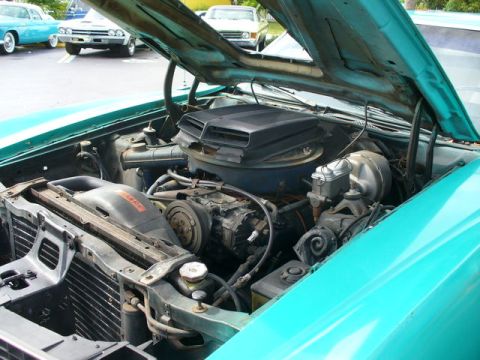 1970 Ford Torino - The engine bay of a teal 1970 Ford Torino is visible with the hood raised, revealing the engine and surrounding components.