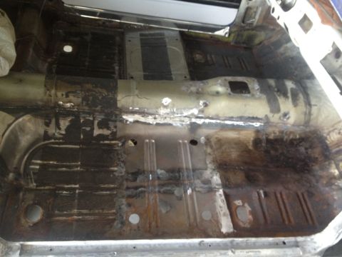 1965 Ford Mustang - The interior floor pan of a car is heavily rusted and shows signs of repair work.