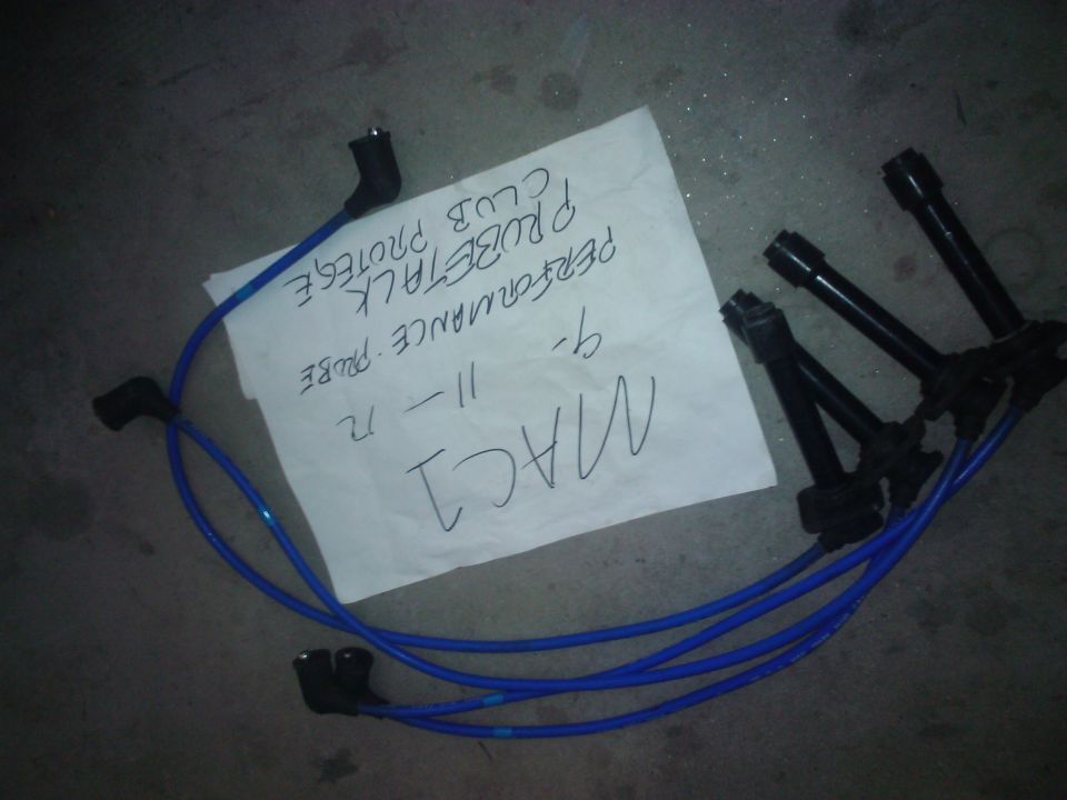 Blue spark plug wires and a white paper with handwritten text 'MAC1 9- 11-12 PERFORMANCE PROBE PROTEGE CLUB PROBETALK'