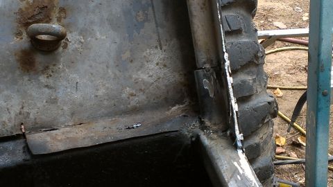 1978 Ford Bronco - Close-up of heavily rusted vehicle body panel and tire tread, with visible welding.