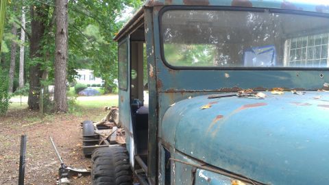 1978 Ford Bronco - This old truck cab is in a state of disrepair, sitting outdoors amongst trees.
