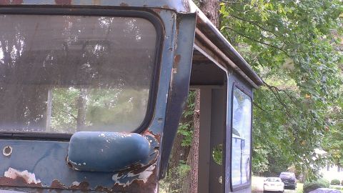 1978 Ford Bronco - The weathered side of a 1978 Ford Bronco cab, with visible rust and peeling paint, stands outdoors.