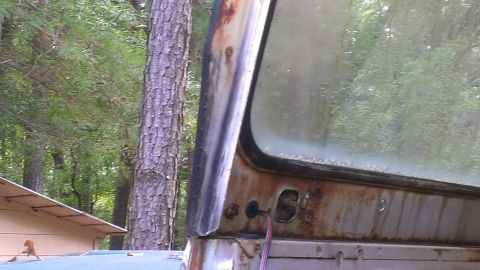 1978 Ford Bronco - Close-up of a weathered vehicle door frame and window, showing signs of rust and age.