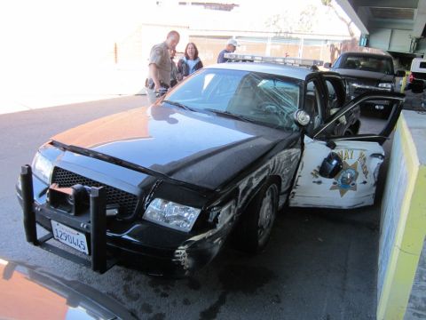 1991 Ford LTD Crown Victoria - A damaged police car sits with its door open, while officers and civilians observe the scene.