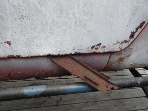 1961 International Scout 80 - Detail of a heavily rusted metal bracket attached to the lower body of a vehicle, indicating extensive wear and tear.