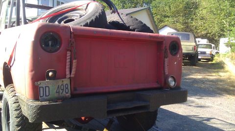 1961 International Scout 80 - The rear of a red 1961 International Scout 80 is visible, with other vehicles parked behind it.