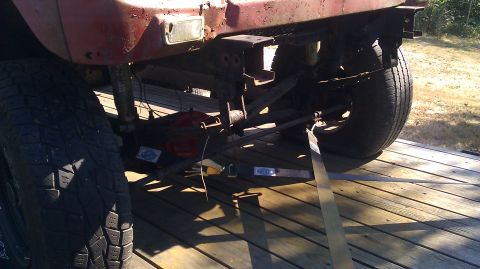1961 International Scout 80 - The rear suspension and axle of a vehicle are secured with straps to a wooden trailer bed.