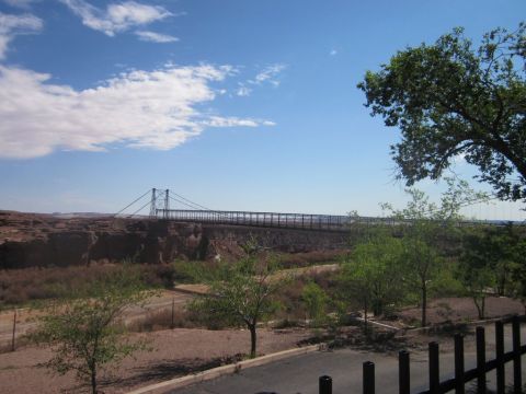 1991 Ford LTD Crown Victoria - A wide shot shows a suspension bridge spanning a dry riverbed under a blue sky with scattered clouds.