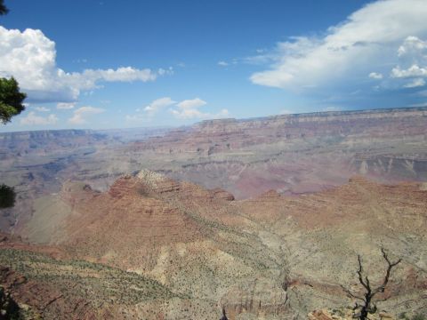1991 Ford LTD Crown Victoria - View of the Grand Canyon's vast geological formations and colorful strata under a partly cloudy sky.