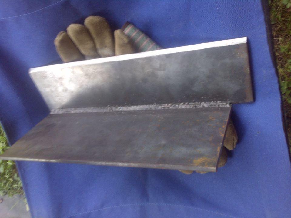 Welded metal part on blue cloth with gloves