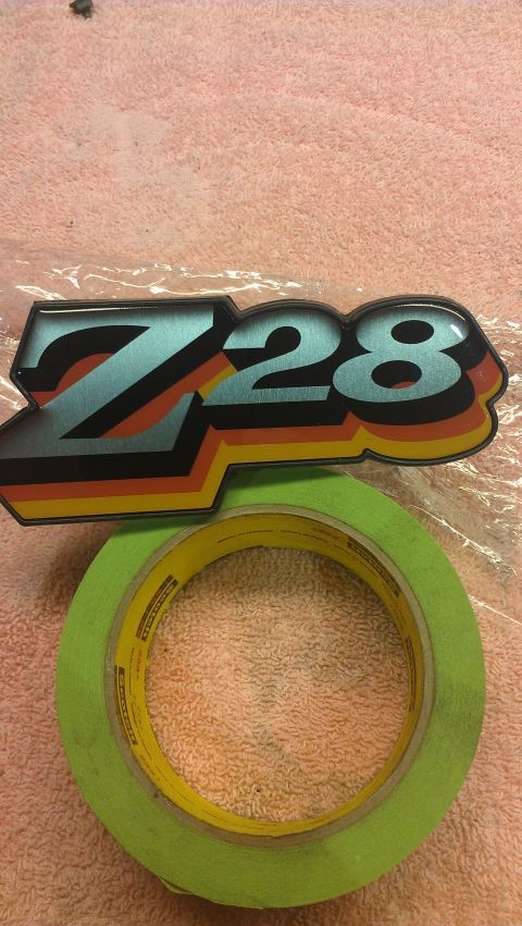 1973 Chevrolet Camaro - A Z28 emblem is shown with a roll of green masking tape on a textured surface.