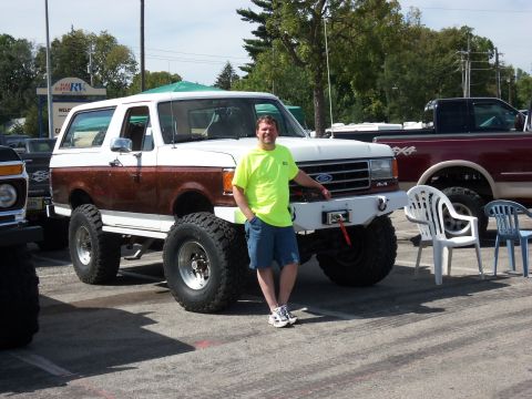 1989 Ford Bronco - Man poses with his lifted 1989 Ford Bronco, a classic 4x4 with custom modifications.