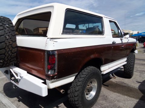 1989 Ford Bronco - This Ford Bronco features a two-tone paint job and a spare tire on the back.