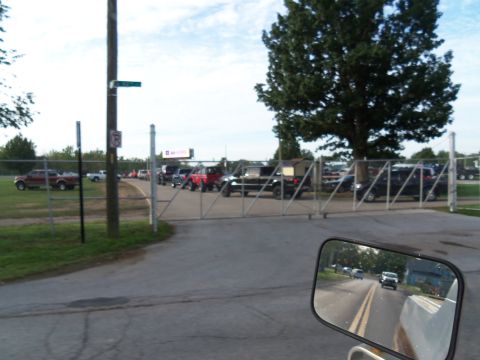 1989 Ford Bronco - Multiple vehicles wait behind a gate on a cloudy day.