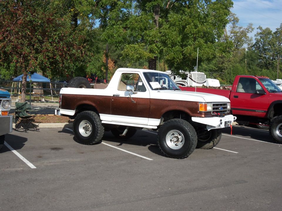 Lifted white and brown pickup truck parked next to a red pickup truck