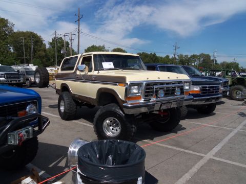 1989 Ford Bronco - This lifted 1978 Ford Bronco is parked in a lot with other vehicles under a cloudy sky.