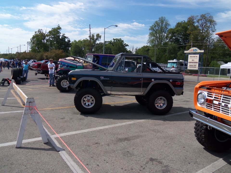 Gray Ford Bronco with lifted suspension and aftermarket wheels, parked in a lot