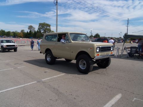1989 Ford Bronco - A tan International Harvester Scout II is shown from the front-right angle, with another vehicle visible in the distance.