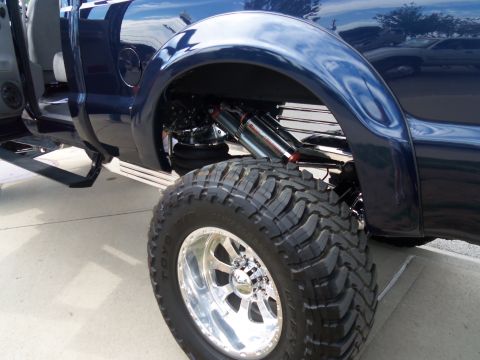 1989 Ford Bronco - Close-up of a lifted pickup truck's rear wheel, suspension, and fender.