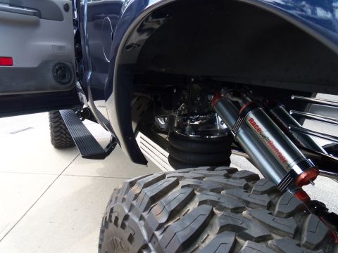 1989 Ford Bronco - This modified truck features air suspension and large off-road tires, with 'RaceRunner' visible on the shocks.