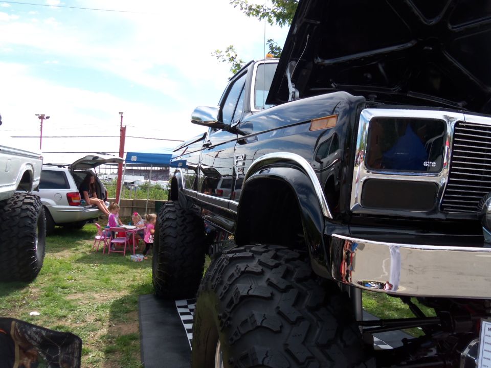 Black lifted truck, 3q-front view, with chrome grille and large tires