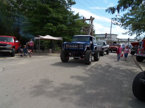 1989 Ford Bronco - A blue lifted SUV is parked on a street, with other vehicles and people around.