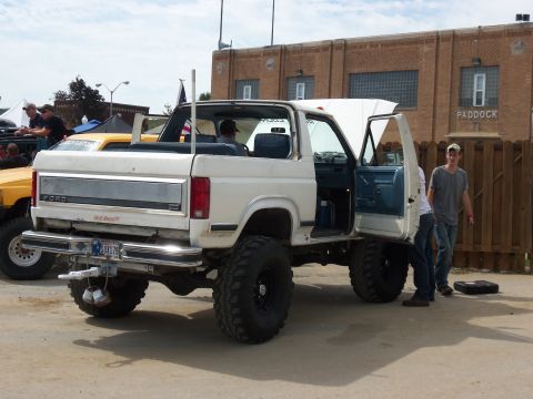 1989 Ford Bronco - A white 1989 Ford Bronco is shown with its doors open and hood up, a lifted suspension and oversized tires.