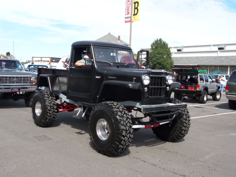 Black lifted pickup truck with large tires and a visible V8 badge on the fender