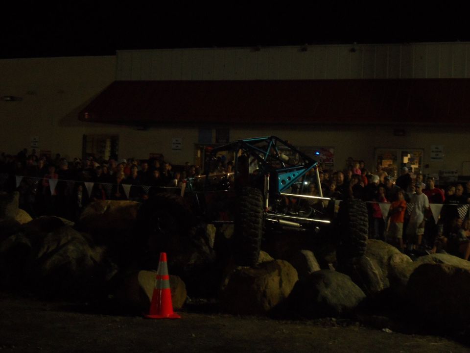 custom off-road buggy with roll cage on rocks in front of crowd