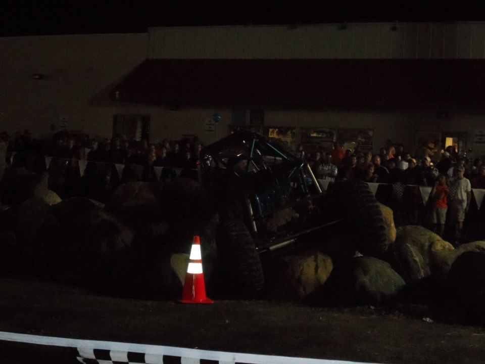 Blue off-road buggy with roll cage on large rocks at night