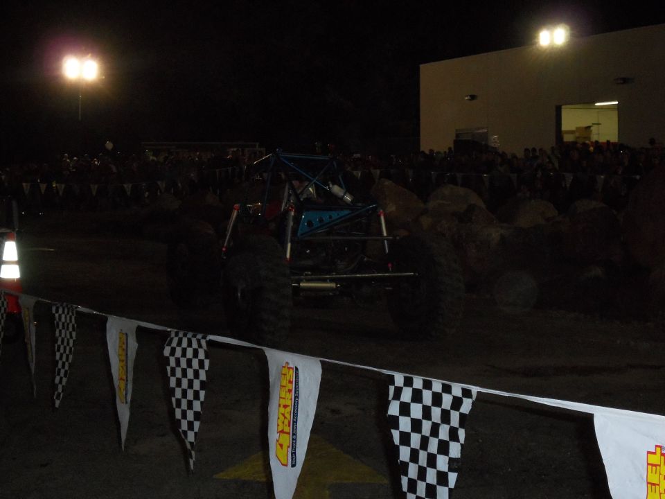 Rear view of a custom off-road buggy with a roll cage and large tires, at night