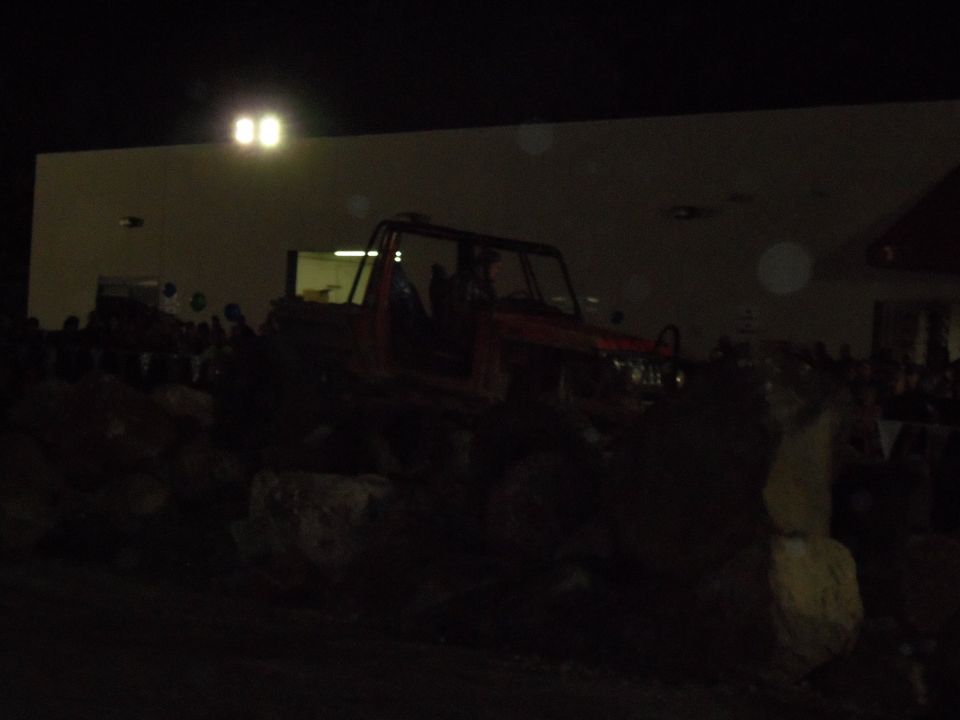 Red off-road vehicle with roll cage parked on large rocks at night