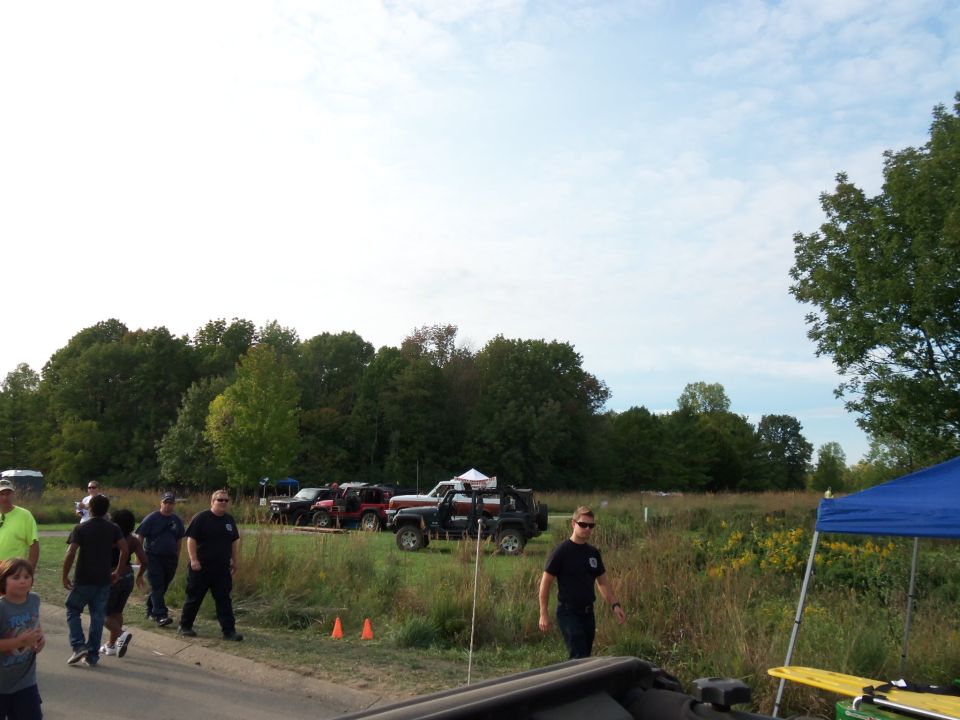 Several SUVs and trucks parked in a grassy field with trees in the background