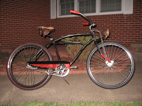 1994 Ford Bronco - A vintage-style bicycle with a black frame and red detailing sits on a paved surface in front of a brick building.