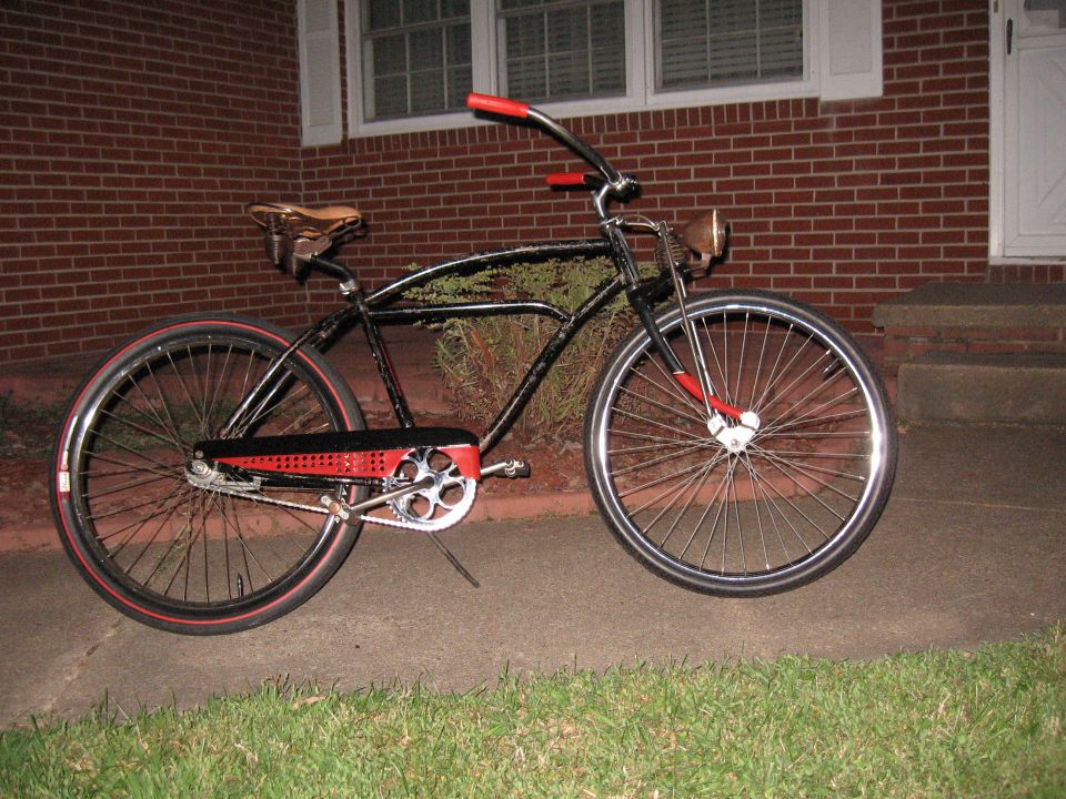 Black cruiser bicycle with red handlebars and accents, side view