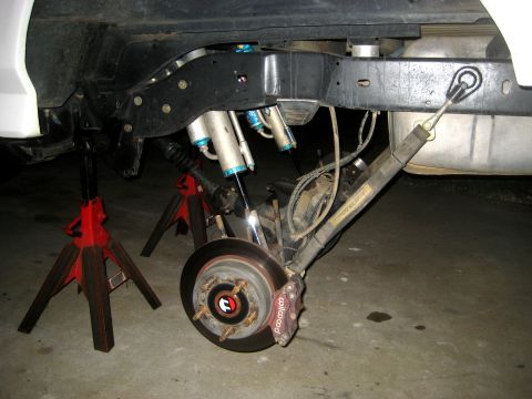 1996 Ford Bronco - Close-up view of the rear suspension system of a vehicle, supported by jack stands.
