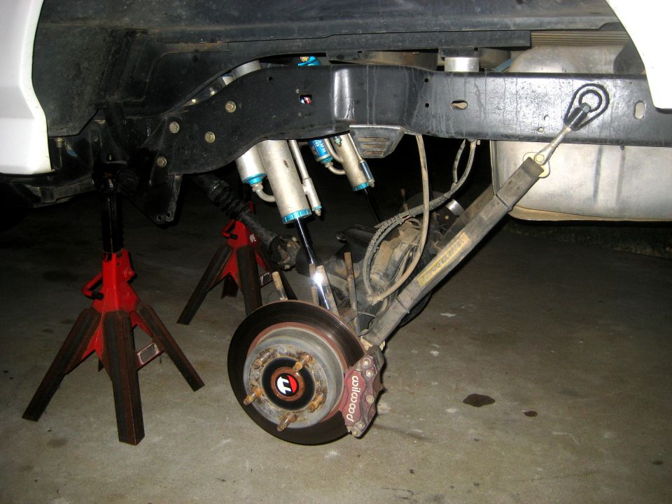 Rear suspension with dual shocks, disc brake, and fuel tank. Vehicle on jack stands