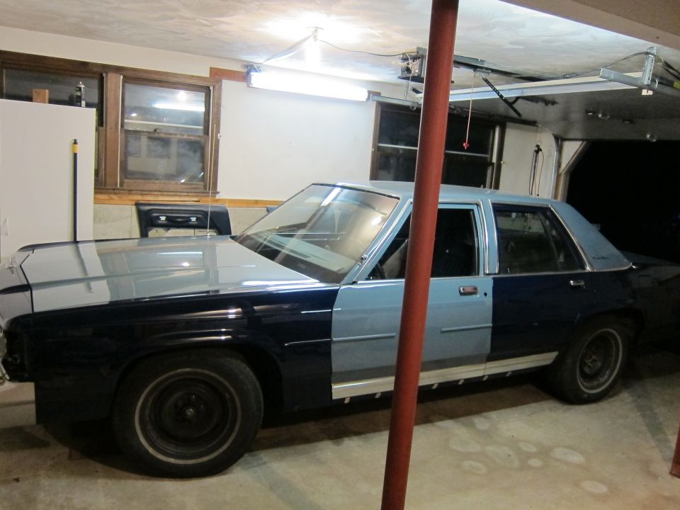 Ford Crown Victoria with two-tone paint job, front half light blue, rear half dark blue. Parked in a garage