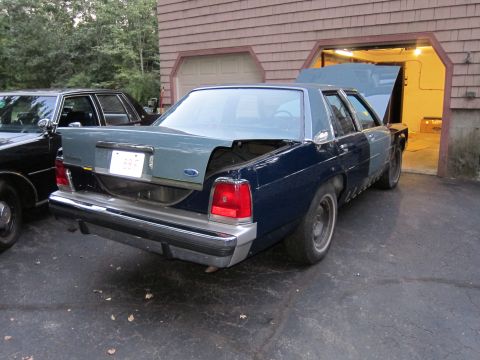 1991 Ford LTD Crown Victoria - Rear view of a dark blue Ford Crown Victoria with its trunk and hood open, parked in a driveway.