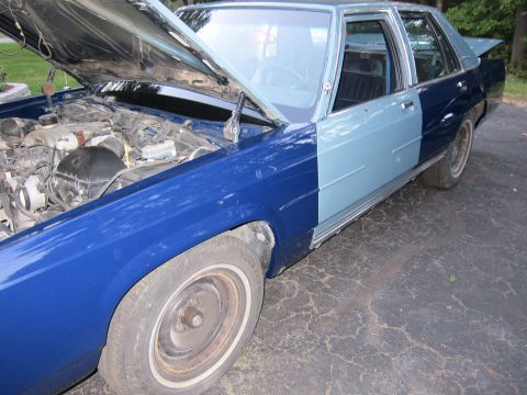 1991 Ford LTD Crown Victoria - This sedan, possibly a Ford Crown Victoria, is shown with its hood open, revealing the engine compartment. The vehicle has a two-tone paint…