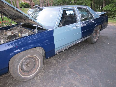 1991 Ford LTD Crown Victoria - This Ford Crown Victoria has a two-tone paint scheme with the hood up, revealing the engine bay.