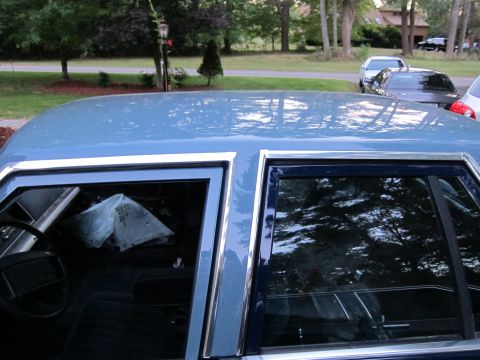 1991 Ford LTD Crown Victoria - A blue sedan is parked in a driveway with other vehicles visible in the background.