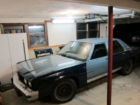 1991 Ford LTD Crown Victoria - A two-tone sedan, possibly a Ford Crown Victoria, sits in a garage with its hood and front fender painted black.