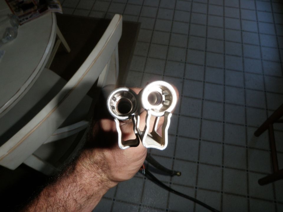 Two fuel line fittings held in a hand, one shiny, one darker