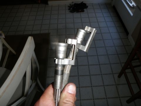 1961 International Scout 800 - A person is holding a metal fuel line fitting with a braided hose attached.