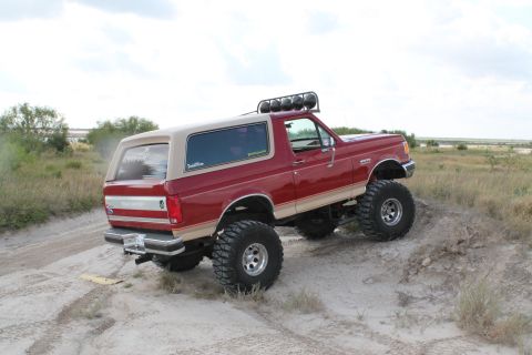 1990 Ford Bronco - This modified Ford Bronco is shown off-road with large tires and a roof-mounted light bar.