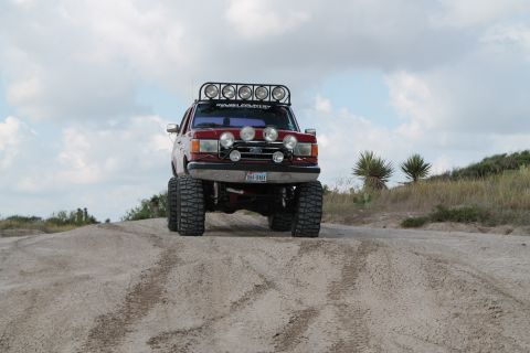 1990 Ford Bronco - Red 1990 Ford Bronco with roof-mounted and bumper lights, lifted for off-roading.