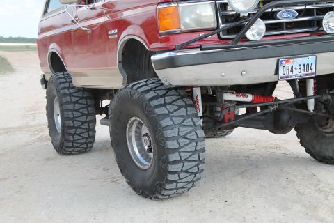1990 Ford Bronco - This modified Ford Bronco features oversized tires and suspension modifications, suggesting off-road use.