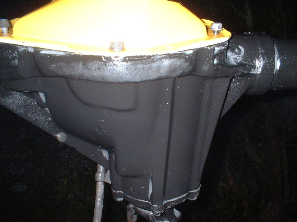 Black-painted axle housing with bright yellow bolt-on differential cover, shot at night